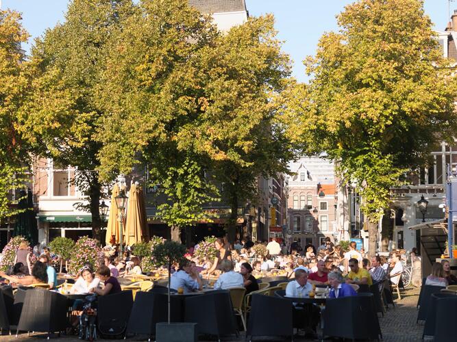 Mensen zitten op een terras in de zon