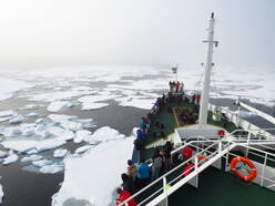 Foto van schip dat ploegt door zee-ijsvelden ten noorden van Spitsbergen op 20 augustus 2019.