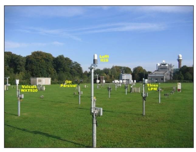 Figure 4. The test field in De Bilt, with the four precipitation type sensors under test indicated in the foreground.