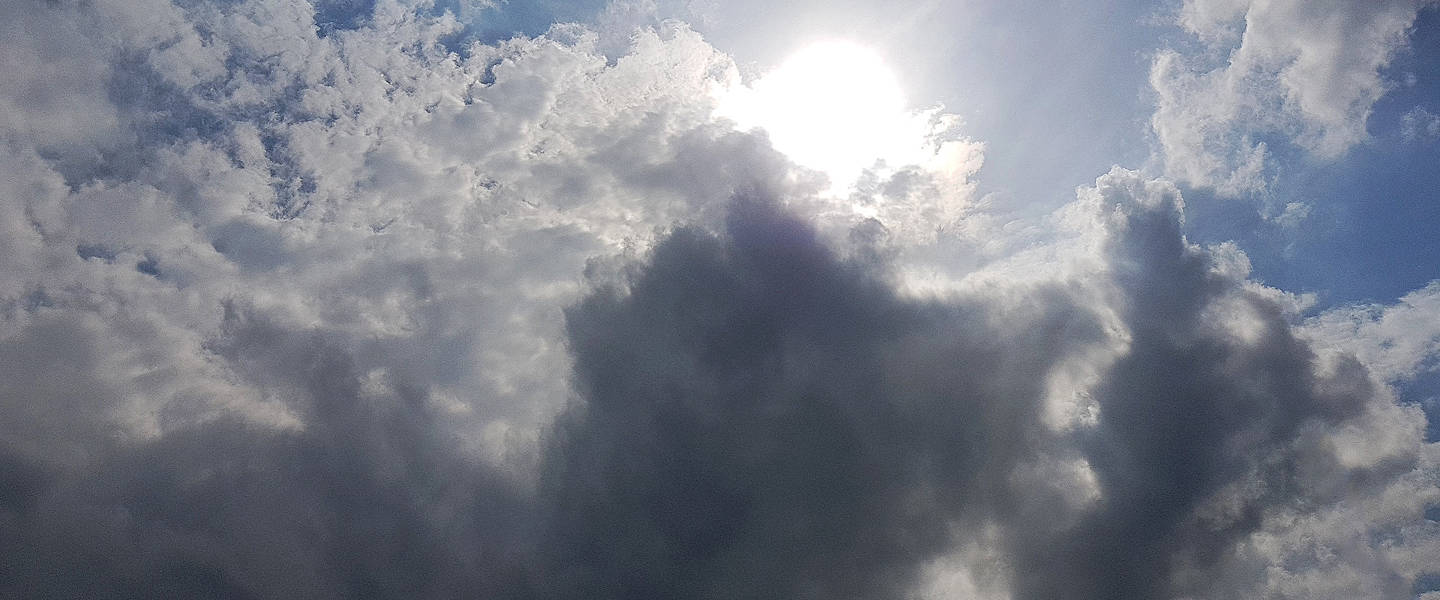 afbeelding van de zon die doorkomt achter de wolken