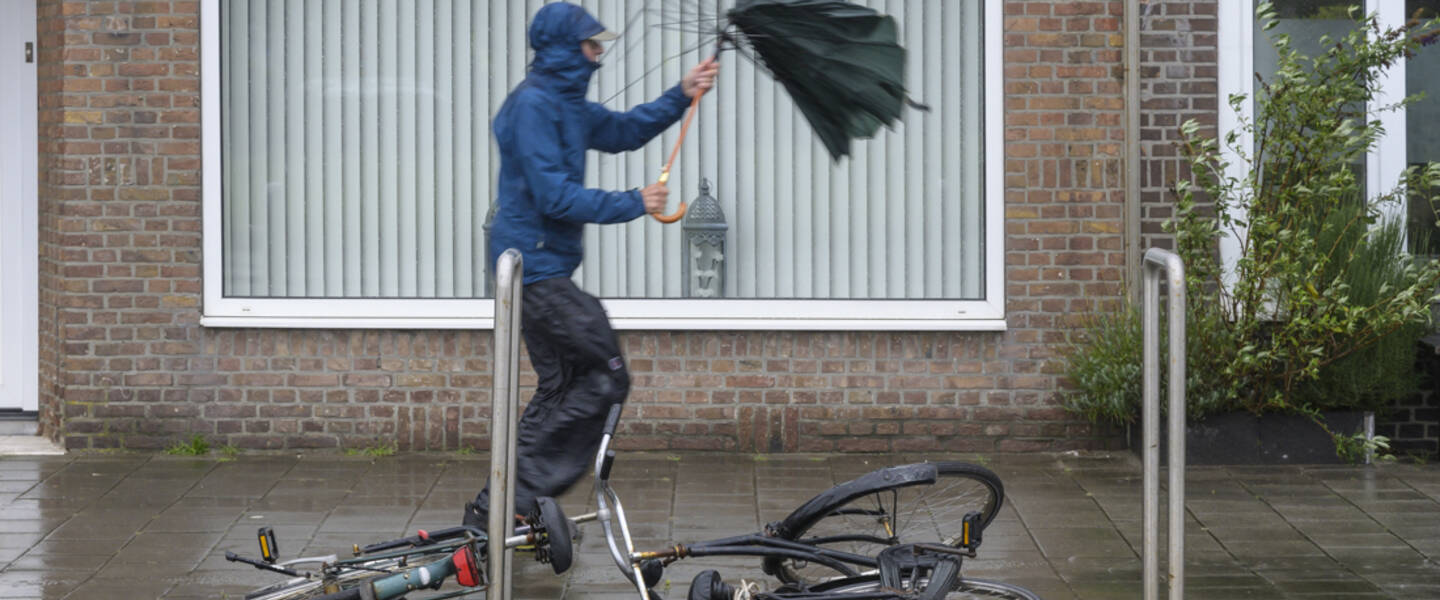 Foto van een man in de regen met een kapotte paraplu 