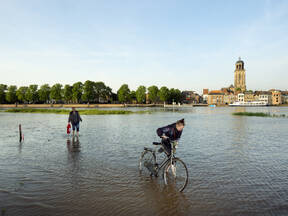 fietser loopt door hoogwater in deventer
