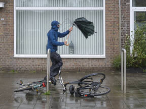 Foto van een man in de regen met een kapotte paraplu 