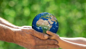 Een oudere en een jongere hand houden samen de aarde vast