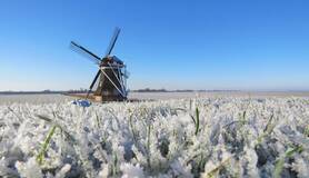 Foto van een molen in besneeuwd landschap