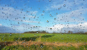 regendruppels voor blauwe lucht en groen weiland
