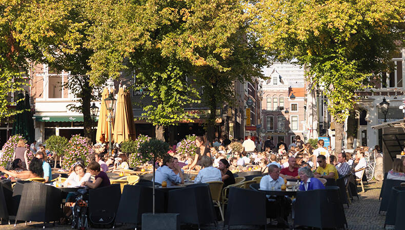 mensen in de zon op terras in Den Haag