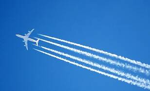 vliegtuig met viegtuigstrepen in blauwe lucht