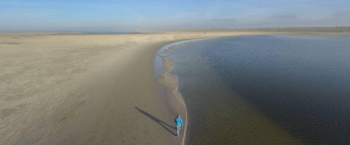 vrouw loopt langs overgang strand en zee