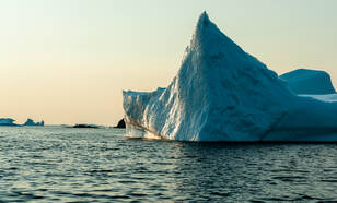 IJsberg drijft in zee bij ondergaande zon