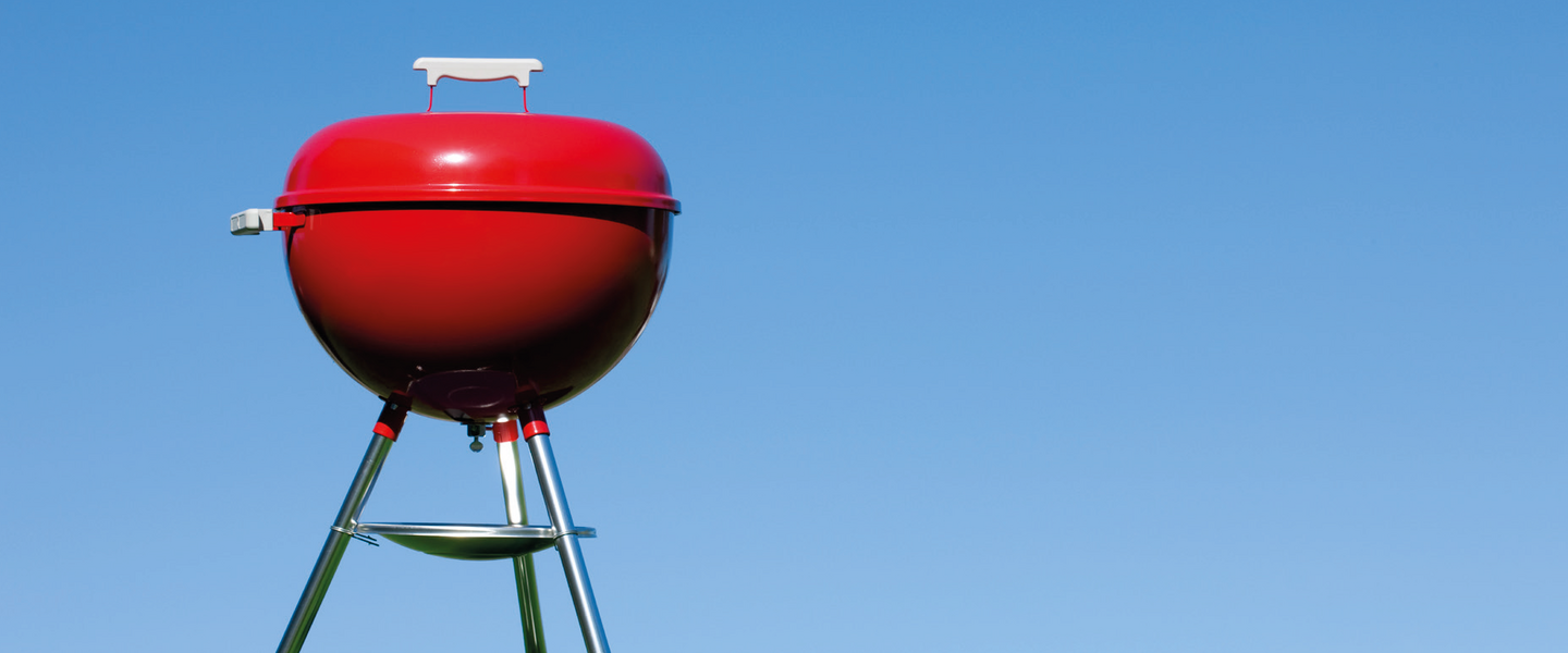 rode barbecue op het gras met strakblauwe lucht