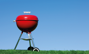 rode barbecue op het gras met strakblauwe lucht