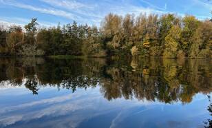 Foto van bomen in herfstkleuren weerspiegeld in een meer