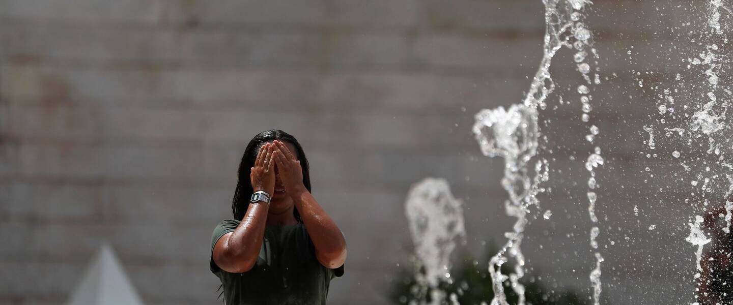 Vrouw zoekt verkoeling bij fontein vanwege extreme hitte in portugal