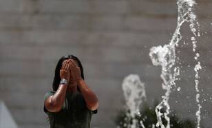 Vrouw zoekt verkoeling bij fontein vanwege extreme hitte in portugal