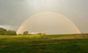 Foto van een dubbele regenboog en bui. 