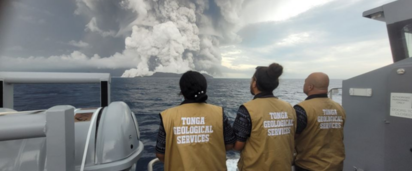 Mensen kijken vanaf een schip naar utbarsting van de Hunga Tonga Vulkaan