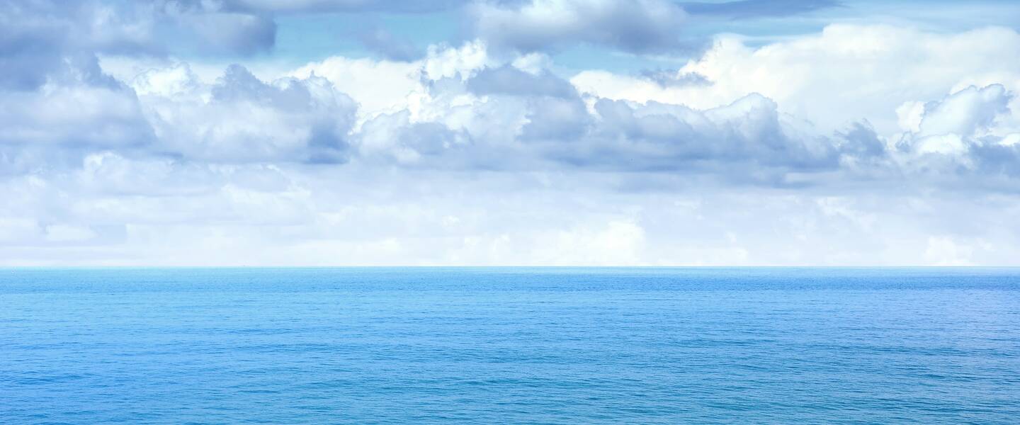 Blauwe oceaan met een wolkenlucht
