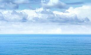 Blauwe oceaan met een wolkenlucht