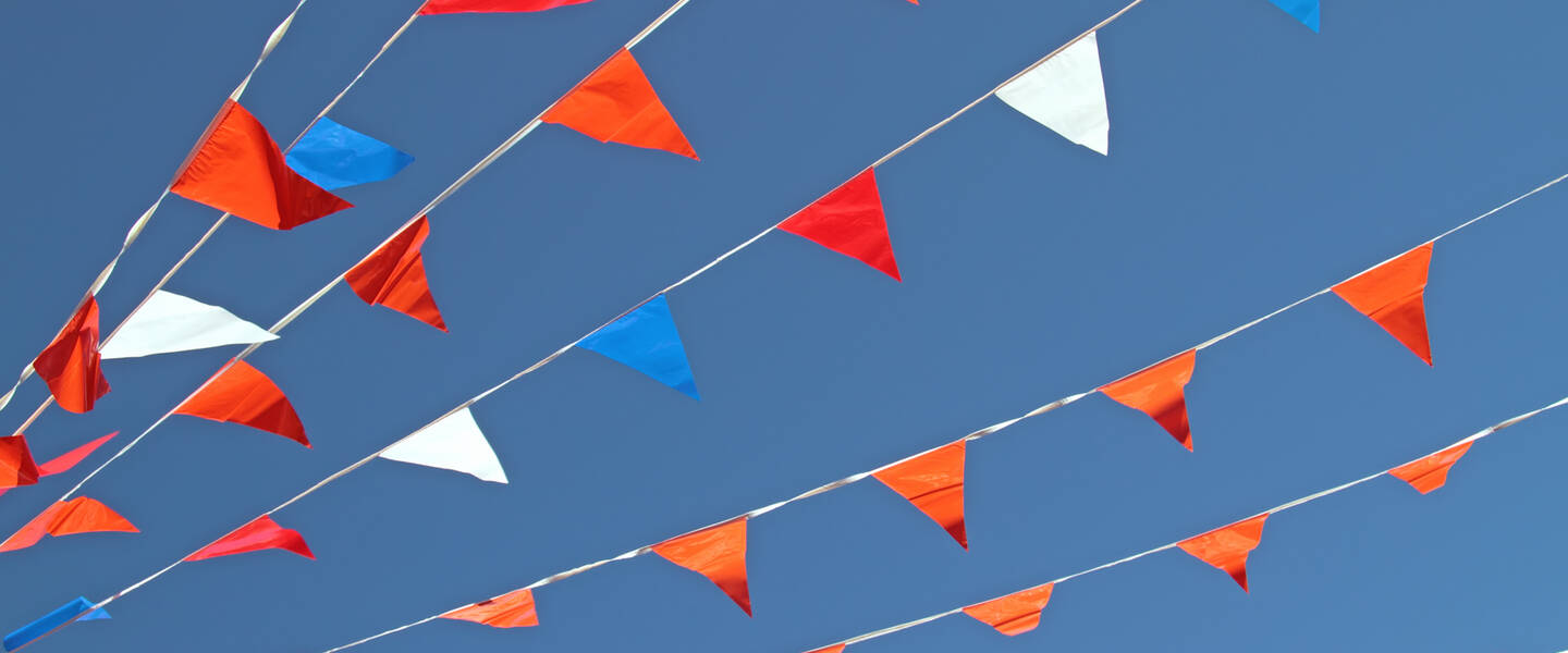Rood-wit-blauwe en oranje vlaggetjes in een blauwe lucht
