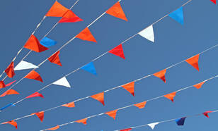 Rood-wit-blauwe en oranje vlaggetjes in een blauwe lucht
