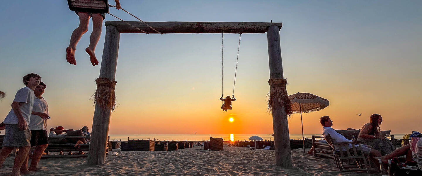 mensen schommelen op het strand bij zonsondergang in augustus 2024