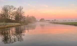 Ochtendrood met mist boven riviertje