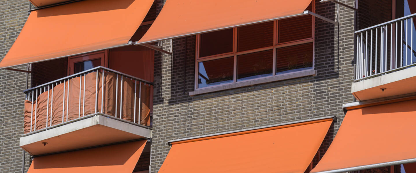 een foto met ramen en oranje zonneschermen 