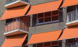 een foto met ramen en oranje zonneschermen 