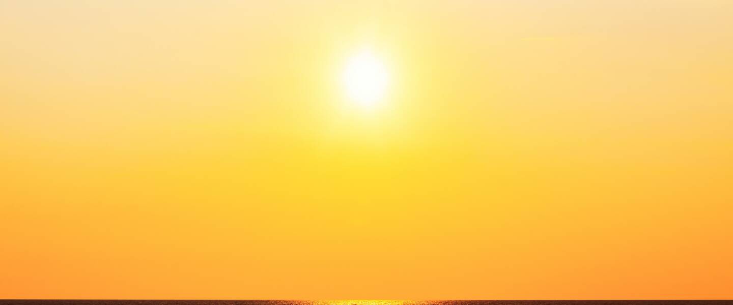 Zon boven oceaan in feloranje gekleurde lucht