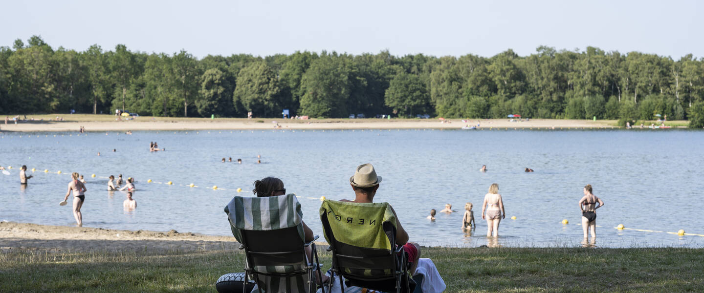 Mensen langs een strandje in de schaduw