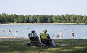 Mensen langs een strandje in de schaduw