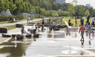 Mensen en kinderen zoeken verkoeling bij het water in Tilburg. 