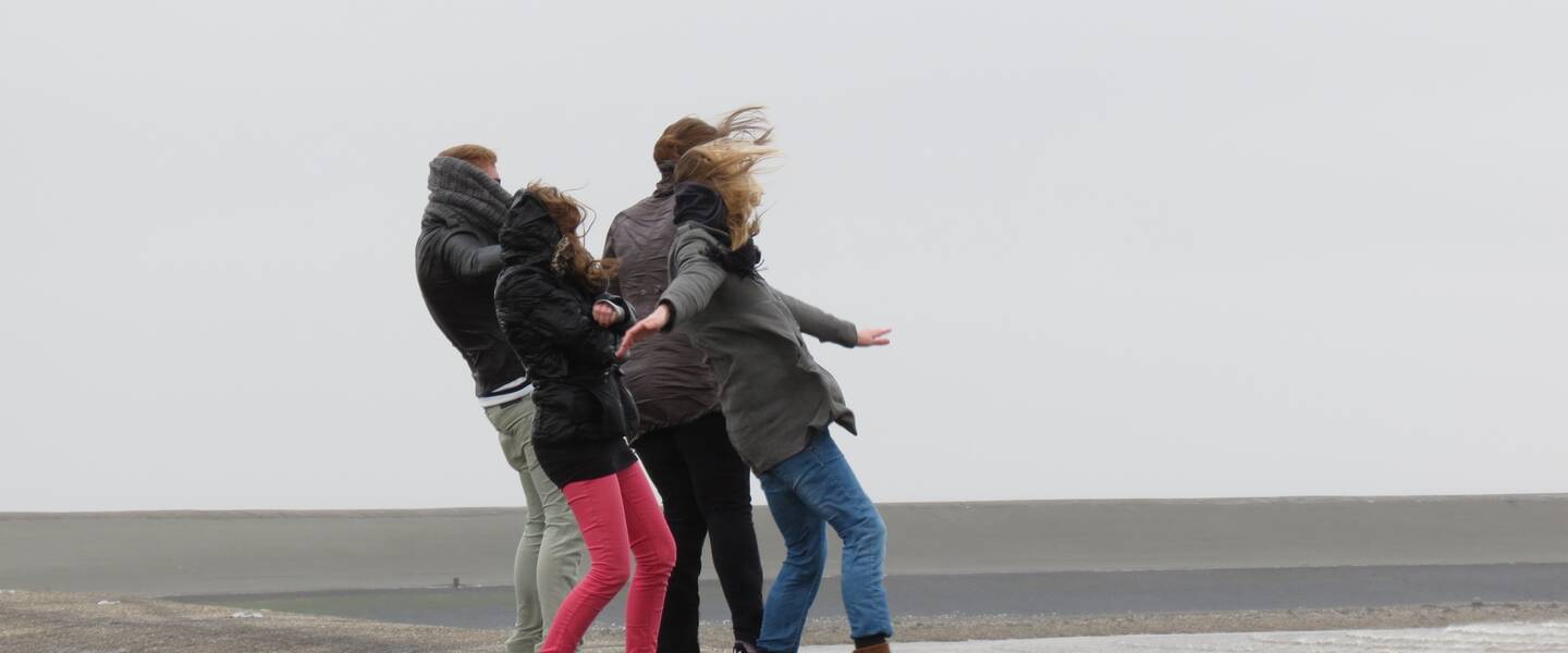 mensen hebben last van de wind aan de kust 