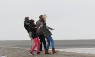mensen hebben last van de wind aan de kust 